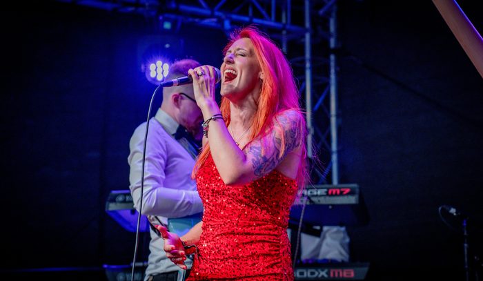 Keely-Marie singing under blue stage lights